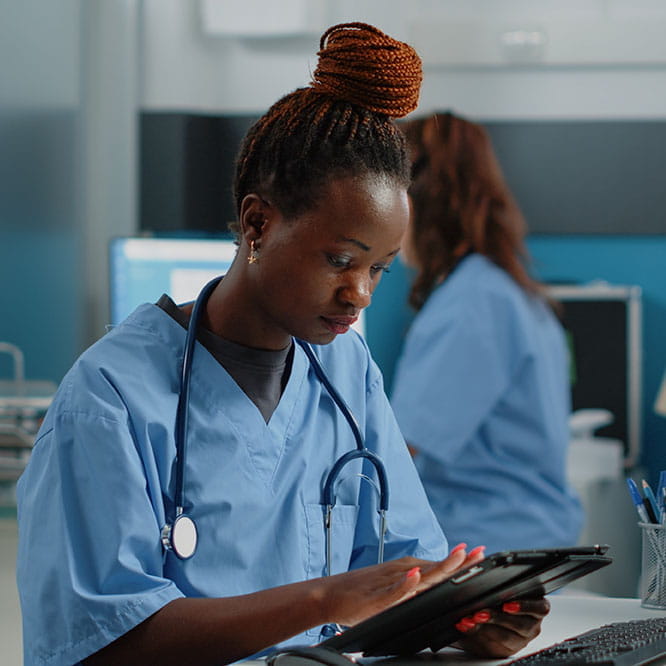 Krankenschwester mit Stethoskop, sitzend am Tablet